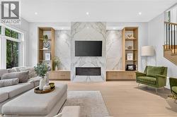 Marble-look fireplace surround with an integrated linear electric fireplace, custom built-in shelving, wood-finish flooring, and recessed lighting - 