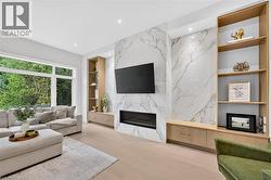 Modern living space featuring an expansive window, light wood-finish flooring, a contemporary fireplace, and built-in shelving with integrated cabinetry - 