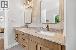 Floating dual vanity with wood-finish cabinetry, integrated sinks, and brass-tone fixtures - 