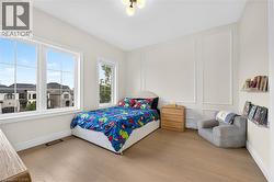 Expansive window arrangement, light wood-finish flooring, accent wall paneling, and a contemporary ceiling light fixture - 