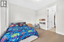 Light wood-finish flooring, white walls with decorative paneling, and a white interior door - 