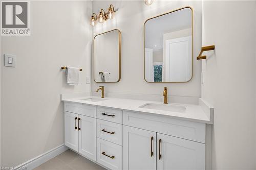 Dual vanity with white cabinetry, gold-finish hardware, rectangular sinks, and integrated countertops - 67 Cielo Court, Hamilton, ON 