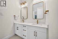 Dual vanity with white cabinetry, gold-finish hardware, rectangular sinks, and integrated countertops - 