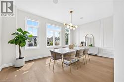 Light wood-finish flooring, multiple pane windows, modern chandelier, recessed lighting, and decorative wall molding - 
