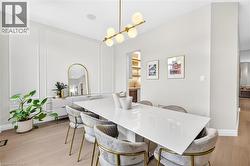Light wood-finish flooring, architectural wall paneling, contemporary linear chandelier with frosted globes, recessed ceiling speakers, and crown molding - 