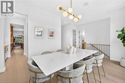 Recessed lighting, wood-finish flooring, white walls, and a modern linear chandelier - 