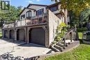 Multi-level residence featuring brick and siding exterior, multiple garage bays, a second-story balcony with metal railings, and exterior wooden stairs leading to the upper entry - 475 Beechwood Drive Unit# 4, Waterloo, ON 