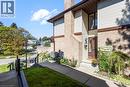Brick and siding exterior with a prominent chimney, concrete walkway, and landscaped garden beds - 475 Beechwood Drive Unit# 4, Waterloo, ON 