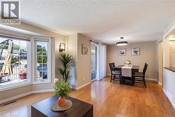 Hardwood-finish flooring, bay window, built-in wall sconce, patio door, and modern overhead light fixture - 