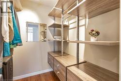 Custom closet system featuring wood-finish shelving, integrated drawers, and a built-in mirror - 
