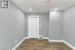 Interior room featuring neutral-tone walls, wood-finish flooring, a white two-panel interior door, and recessed ceiling lighting - 