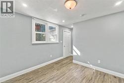 Interior room featuring wood-finish flooring, dual-pane window, flush-mount ceiling lighting, and a six-panel interior door - 