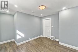 Neutral-toned walls, wood-finish flooring, recessed lighting, and a paneled interior door - 