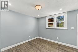 Interior space featuring wood-finish flooring, neutral-toned walls, recessed lighting, a semi-flush mount ceiling fixture, and a dual-pane window with white trim - 