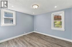 Interior room featuring wood-finish flooring, two double-hung windows with white casing, and a central ceiling-mounted light fixture - 