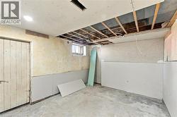Unfinished interior space featuring partial drywall installation, exposed ceiling joists, concrete flooring, and a single-pane window - 