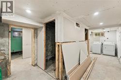 Unfinished utility space featuring concrete flooring, recessed lighting, exposed structural framing, and two windows - 