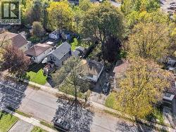 Aerial perspective of the residential lot featuring mature trees, paved driveway access, and established landscaping - 