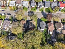 Aerial perspective of a residential lot featuring a detached structure, private paved driveway, fenced perimeter, and mature trees - 