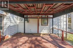 Covered outdoor deck featuring a red-toned wood-finish surface, exposed structural framing, metal roofing, and railings - 