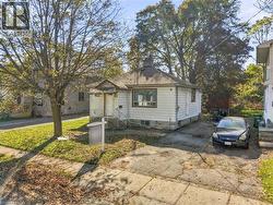 Single-story exterior featuring white horizontal siding, a hipped roofline, stone foundation detail, a front-facing gable, and an attached concrete driveway - 