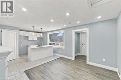 Open-concept interior featuring wood-finish flooring, a kitchen island with stone-surface countertop, recessed lighting, and dual pendant light fixtures - 