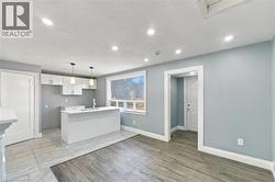Kitchen featuring white cabinetry, a center island with a stone-finish countertop, recessed lighting, wood-finish flooring, and a large picture window - 