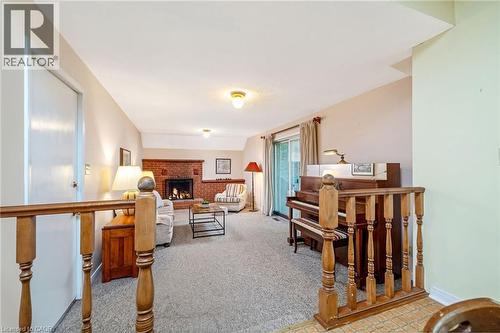 Spacious living area featuring a brick fireplace, sliding glass door, and neutral carpeting - 12 Mullen Place, Glen Williams, ON 