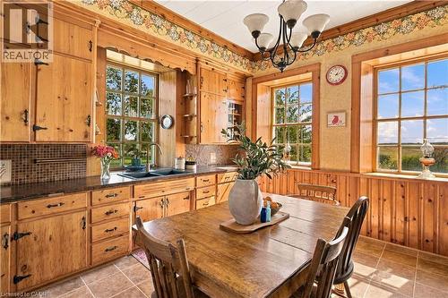 Warm wood cabinetry throughout the kitchen features ample storage, a tile backsplash, and stainless steel hardware - 2744 Bleams Road, New Hamburg, ON 