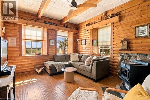 Wood-plank walls and ceiling beams, wood-finish flooring, stone fireplace, and multiple windows - 2744 Bleams Road, New Hamburg, ON 