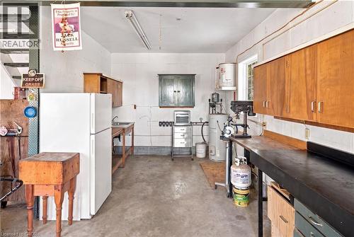 Concrete flooring with a utility sink, wood cabinetry, and a work bench - 2744 Bleams Road, New Hamburg, ON 