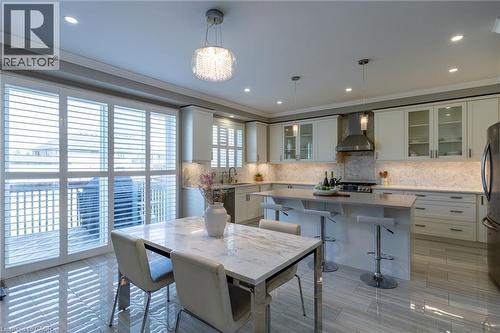 Kitchen featuring white cabinetry, a large center island, stainless steel appliances, and a full tile backsplash - 455 Equestrian Way, Cambridge, ON 