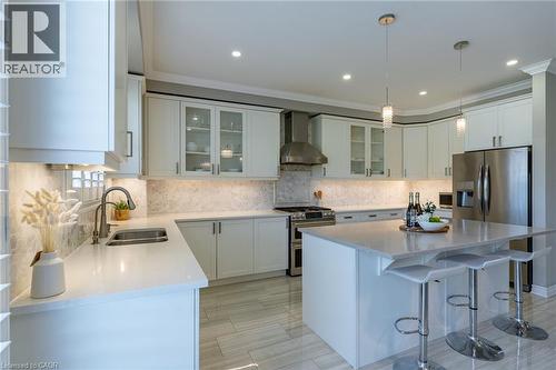 Contemporary kitchen featuring white cabinetry, light-toned countertops, stainless steel appliances, a center island with seating, and recessed lighting - 455 Equestrian Way, Cambridge, ON 
