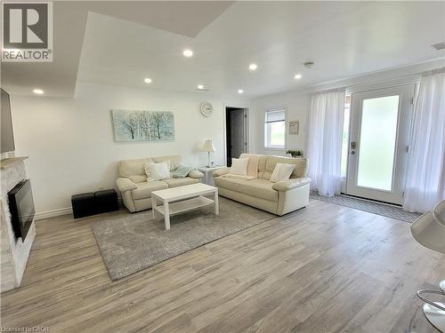 Wood-finish flooring, recessed lighting, white walls, built-in fireplace with stone surround, and sliding glass door with frosted privacy panel - 455 Equestrian Way, Cambridge, ON 
