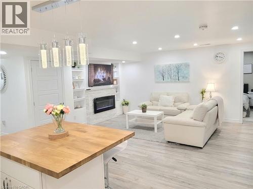 Modern pendant lighting, wood-finish flooring, built-in shelving, electric fireplace, and a light wood countertop - 455 Equestrian Way, Cambridge, ON 