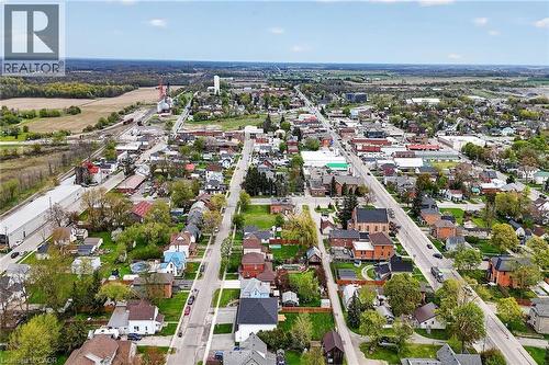 Aerial perspective showcasing a residential and commercial area with visible streets, various building types, and surrounding agricultural fields - 45A Howard Street, Hagersville, ON 
