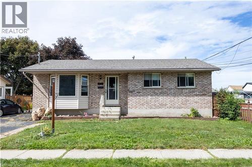 Brick exterior with shingle roofing, featuring a front entry door with storm door, and a concrete pathway - 120 Union Street S, Cambridge, ON 