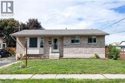 Brick exterior with shingle roofing, featuring a front entry door with storm door, and a concrete pathway - 