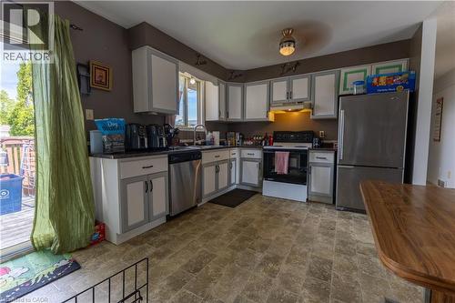Kitchen featuring white cabinetry with gray trim, stainless steel appliances, dark countertops, and patterned floor tile - 120 Union Street S, Cambridge, ON 