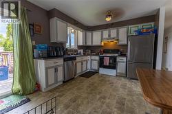 Kitchen featuring white cabinetry with gray trim, stainless steel appliances, dark countertops, and patterned floor tile - 