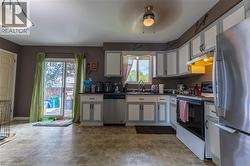 Kitchen featuring L-shaped cabinetry, stainless steel appliances, a ceiling fan with integrated lighting, and direct access to an outdoor area via sliding glass doors - 