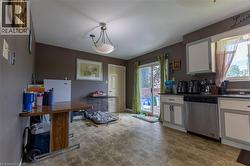 Kitchen with light-toned floor tiles, white and gray cabinetry, dark countertops, and a stainless steel dishwasher - 