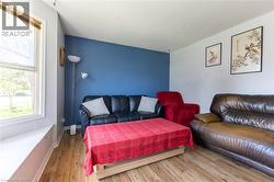 Wood-finish flooring with a white trim, featuring a window and a contrasting accent wall - 
