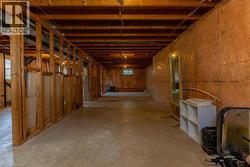 Expansive unfinished basement featuring concrete flooring, exposed wood framing, and ceiling joists - 