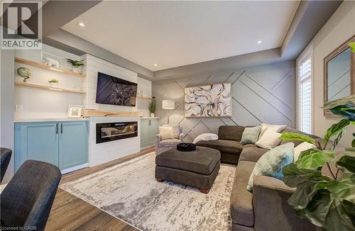 Custom built-in cabinetry with light-toned countertops, integrated electric fireplace, wood-finish flooring, accent wall paneling, and recessed ceiling lighting - 35 Greyhawk Street, Kitchener, ON 