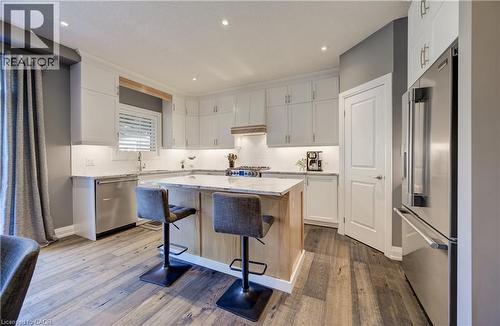Kitchen featuring white cabinetry, light-toned wood-finish flooring, stainless steel appliances, a center island with seating, and recessed lighting - 35 Greyhawk Street, Kitchener, ON 