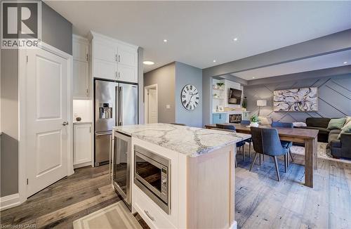 Open-concept living area with wood-finish flooring, a kitchen island featuring a light-toned countertop, and stainless steel appliances - 35 Greyhawk Street, Kitchener, ON 