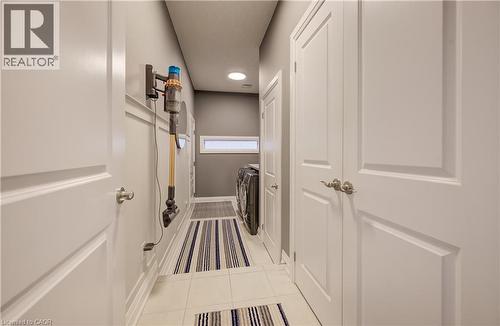 Laundry area featuring light tile flooring, a horizontal window, and panel doors with satin nickel hardware - 35 Greyhawk Street, Kitchener, ON 