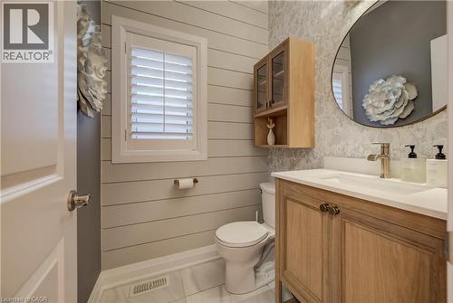 Shiplap wall paneling, plantation shutters, natural wood vanity with integrated sink, brass-finish faucet, and a wall-mounted wood cabinet with glass doors - 35 Greyhawk Street, Kitchener, ON 
