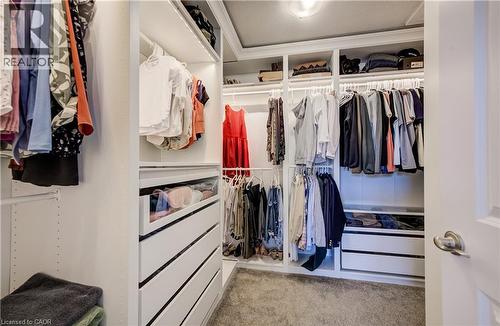 Custom closet system featuring built-in shelving, multiple hanging rods, integrated drawers, and recessed lighting - 35 Greyhawk Street, Kitchener, ON 